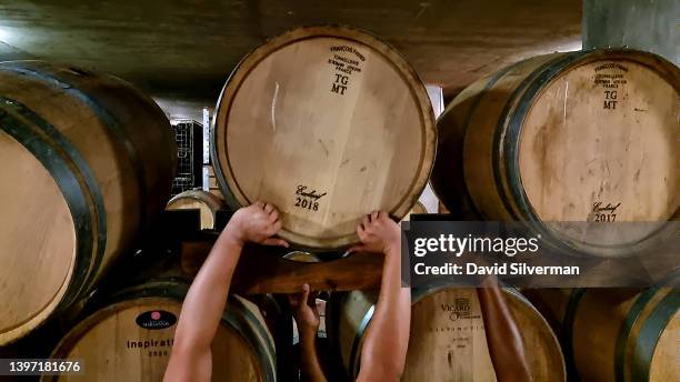 Cavalli Estate winery workers lift a wine cask into place where South African woman winemaker Malie McGregor is head of wine production during...