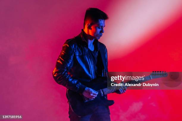 performance of a rock guitarist playing a musical song on a guitar in neon light - solo performance stock pictures, royalty-free photos & images