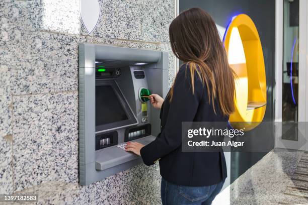 woman withdrawing money from credit card - hole in wall stock pictures, royalty-free photos & images