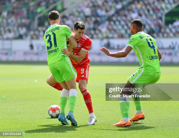 Robert Lewandowski of FC Bayern Muenchen is challenged by Yannick Gerhardt and Maxence Lacroix of VfL Wolfsburg during the Bundesliga match between...