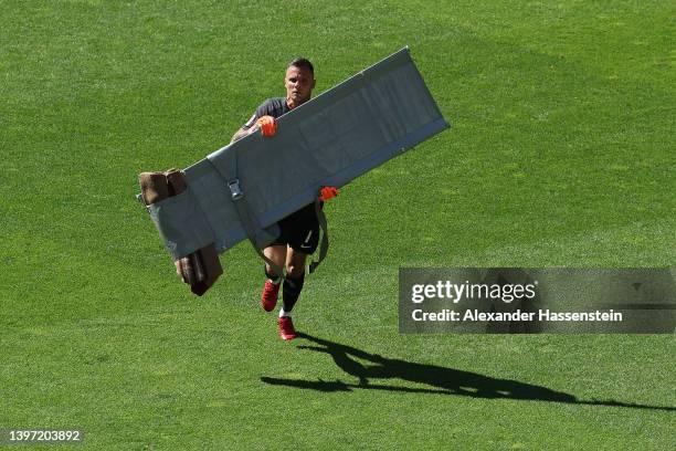 Rafal Gikiewicz carries the stretcher onto the pitch for their teammate Niklas Dorsch of FC Augsburg as they receive medical treatment during the...