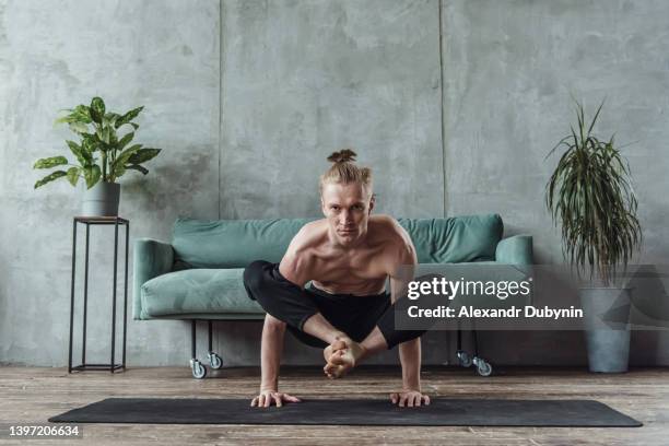 yogi man practices yoga in the living room near the sofa. sports at home - turner contemporary stock-fotos und bilder