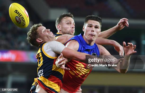 Eric Hipwood of the Lions has a mark spoiled by Mitchell Hinge and Brodie Smith of the Crows during the round nine AFL match between the Adelaide...