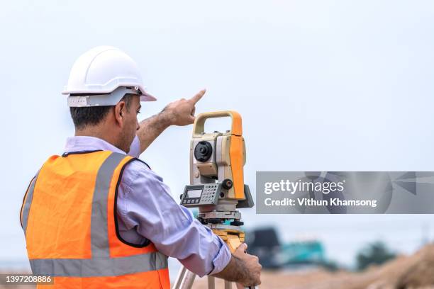 surveyor and survey equipment on construction site, land and soil development, survey equipment, theodolite for measurement construction work, civil engineer. - civil engineering fotografías e imágenes de stock