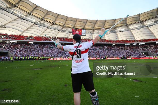 Fan celebrates on the pitch with their right foot in a cast after their sides victory, which means VfB Stuttgart avoid the relegation play offs in...