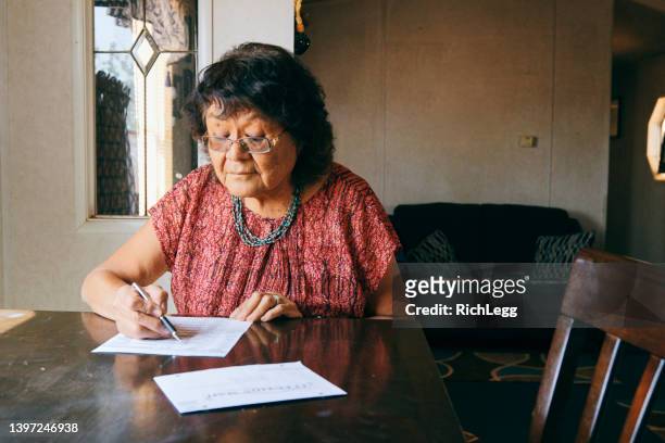 woman voting with a mail in election ballot - voting by mail stockfoto's en -beelden