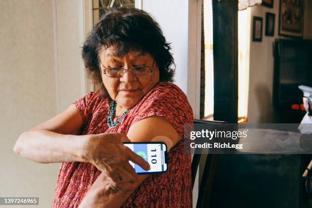 senior woman checking blood glucose level on an app - glucose stockfoto's en -beelden