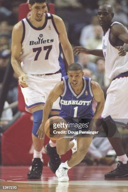 Guard Tyrone Bogues of the Charlotte Hornets dribbles the ball down the court as center Gheorghe Muresan of the Washington Bullets watches at the US...