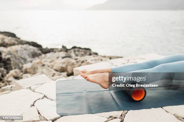 woman massaging legs and calf muscles with black massage roll. roller massager, self massage and healthy lifestyle - female muscular calves stockfoto's en -beelden