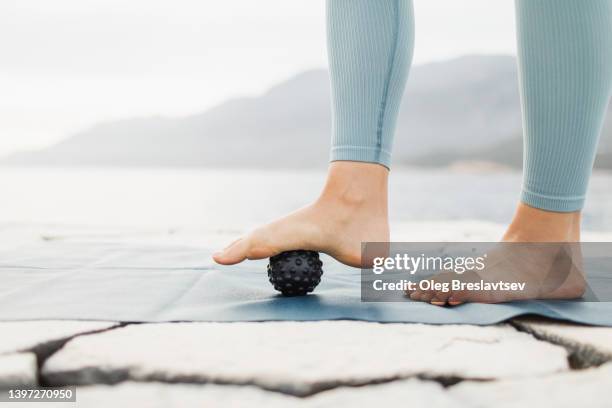 woman massaging foot with black massage ball. roller massager, self massage and healthy lifestyle - woman foot massage stock pictures, royalty-free photos & images