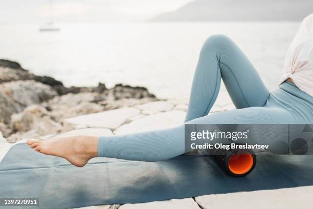 woman massaging legs and hips with black massage roll. roller massager, self massage and healthy lifestyle - cellulit bildbanksfoton och bilder