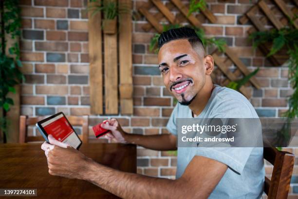 man with vitiligo using credit card - systemic lupus erythematosus stock pictures, royalty-free photos & images