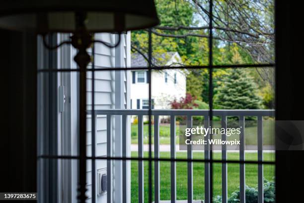 view outside looking through window from dark home interior - security screen stockfoto's en -beelden