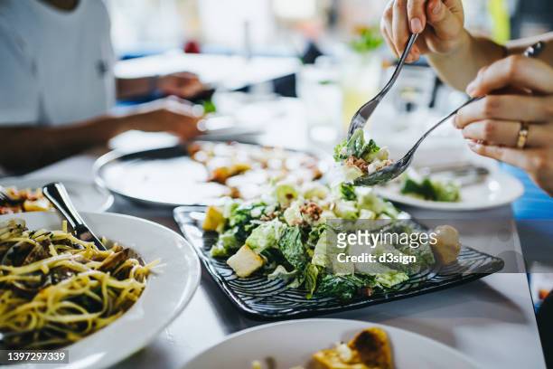 cropped shot of a group of friends enjoying assorted dishes in a restaurant, sharing fresh caesar salad and having a good time together. social gathering and lifestyle concept - garden salad stock pictures, royalty-free photos & images