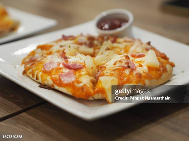 pizza hawaiian on top with ham, bacon, pineapple and pizza sauce cheese in white plate with tomato sauce, food background - hawaiian pizza stock pictures, royalty-free photos & images