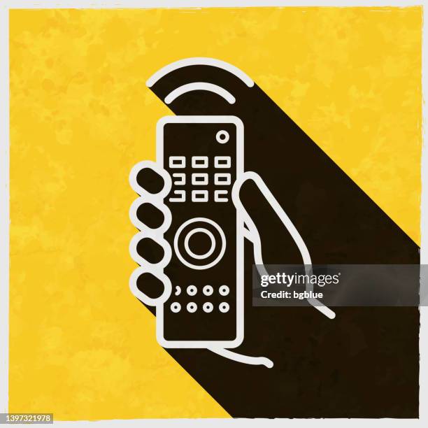 hand with remote control. icon with long shadow on textured yellow background - holding remote control stock illustrations