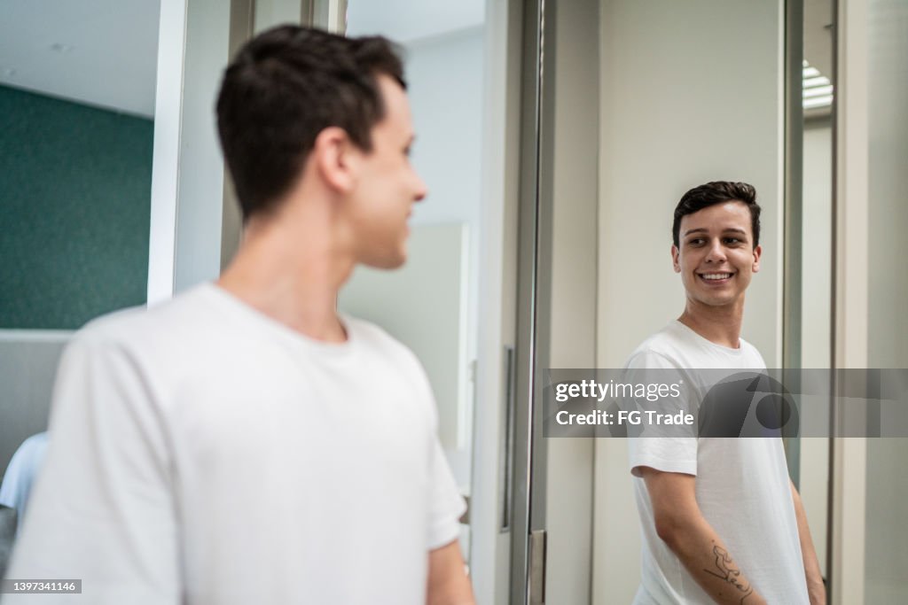 Young man looking in the mirror at home