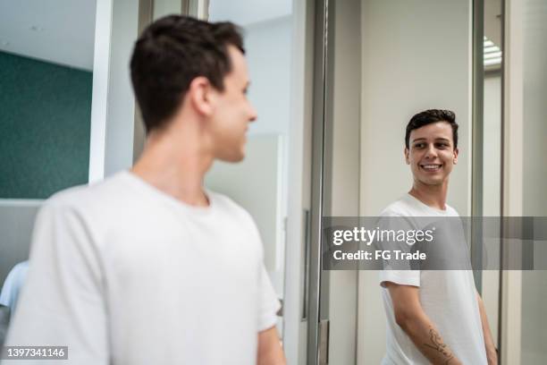 young man looking in the mirror at home - fitting room stock pictures, royalty-free photos & images