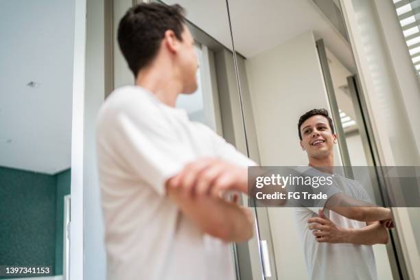 young man getting dressed and looking in the mirror at home - bedroom vanity stock pictures, royalty-free photos & images