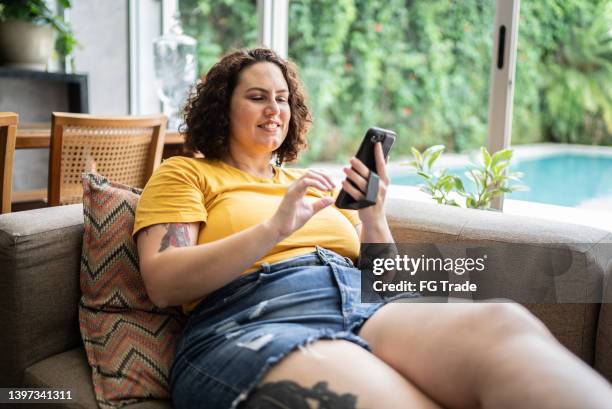 femme adulte utilisant le téléphone portable à la maison - mannequin grande taille photos et images de collection