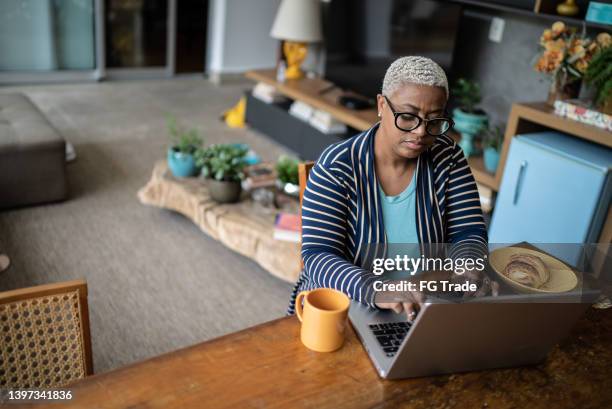 mature woman working on the laptop at home - generation x stock pictures, royalty-free photos & images