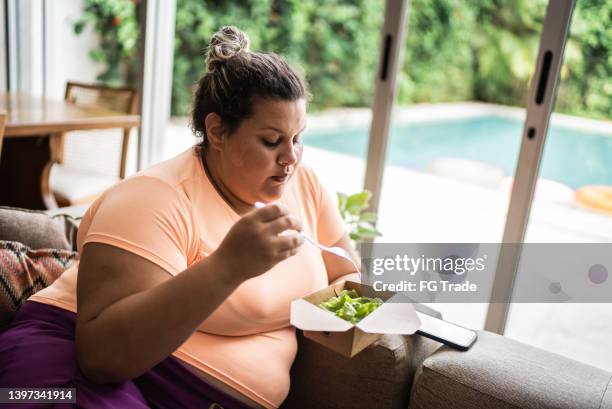 mid adult woman eating salad at home - obesity concept stock pictures, royalty-free photos & images