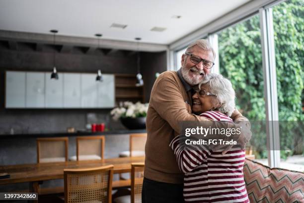 senior couple hugging each other at home - retired couple stockfoto's en -beelden