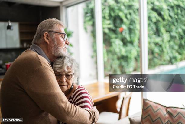 senior couple hugging each other at home - husband stockfoto's en -beelden