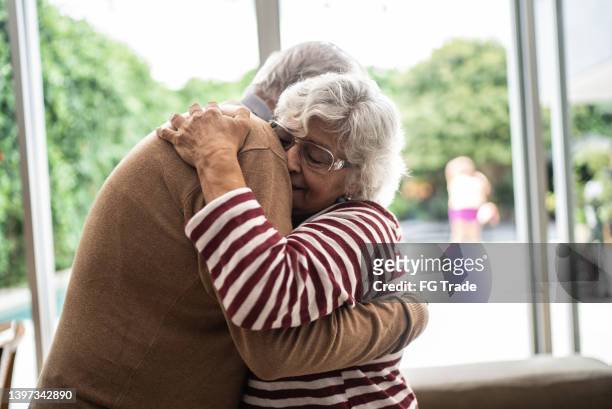 älteres paar umarmt einander zu hause - schmerzfrei stock-fotos und bilder