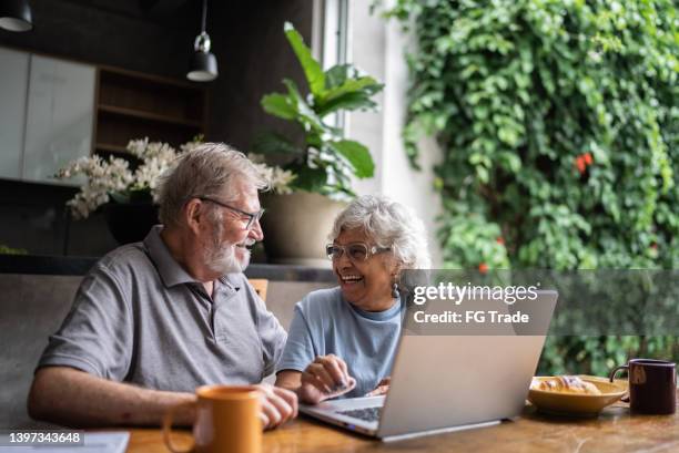 senior couple talking about home finances and using the laptop at home - 401k stock pictures, royalty-free photos & images