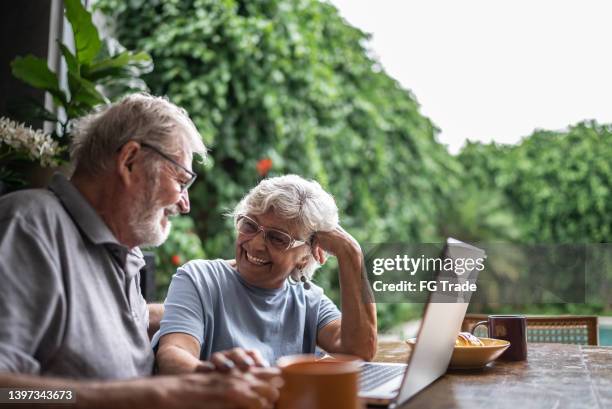 happy senior couple using the laptop at home - senior couple laptop stock pictures, royalty-free photos & images