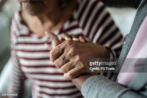 nurse or home caregiver and senior woman holding hands at home - dementia 個照片及圖片檔
