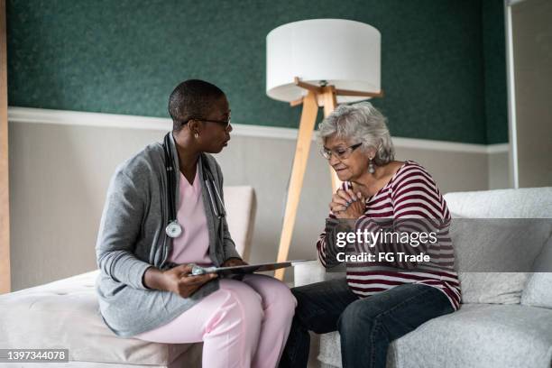 doctor talking to a senior woman in the bedroom - nurse praying stock pictures, royalty-free photos & images