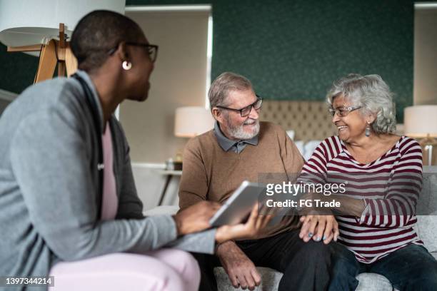 feliz pareja de ancianos celebrando buenas noticias hablando con enfermera / cuidador en el hogar - visita doméstica fotografías e imágenes de stock