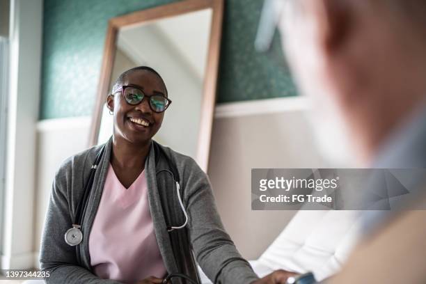 doctor talking to a senior man in the bedroom - senior care stock pictures, royalty-free photos & images