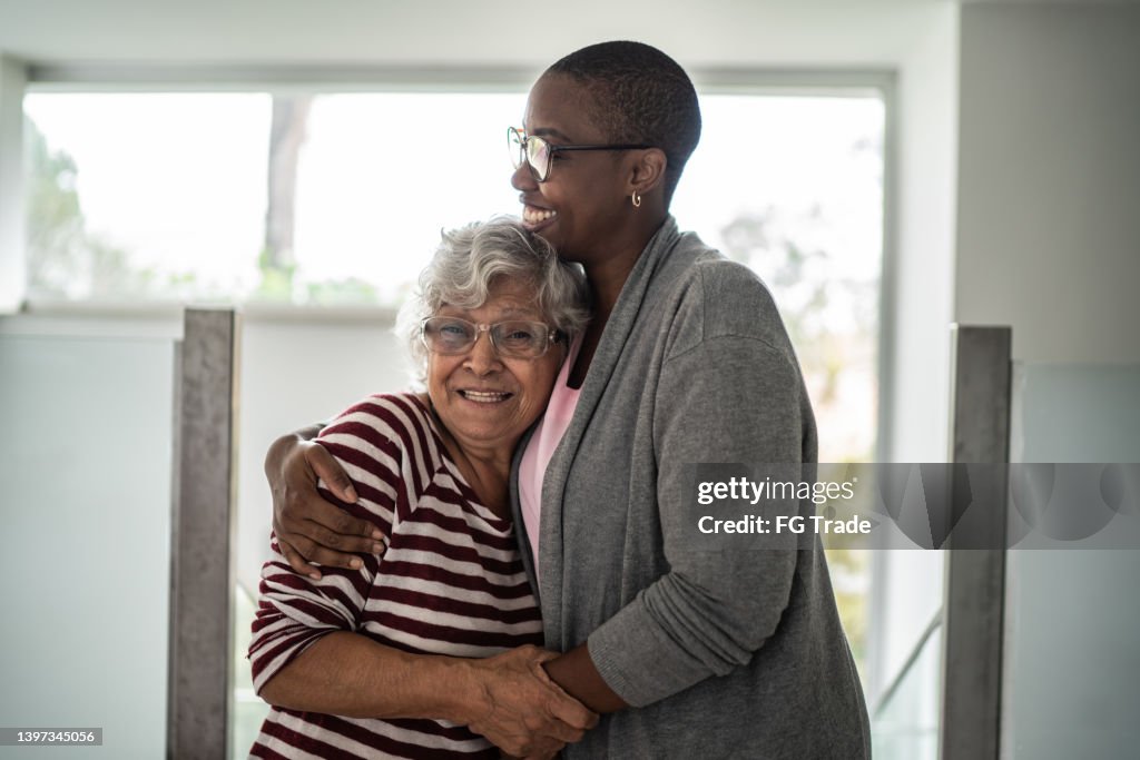 Nurse and senior woman embracing at home