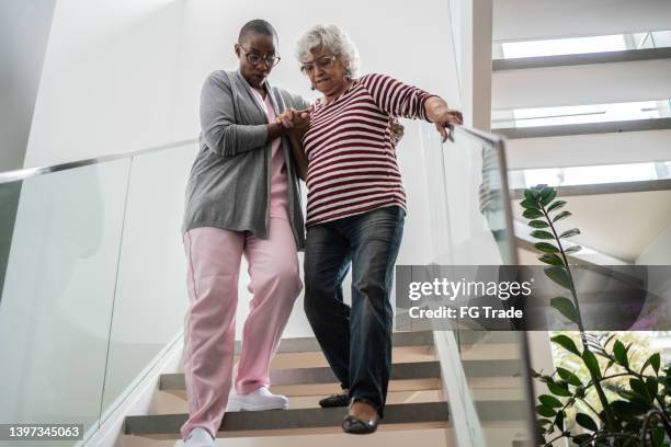 nurse helping a senior woman walking the stairs - parkinsons disease stock pictures, royalty-free photos & images