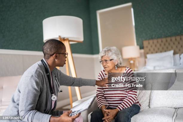 doctor talking to a senior woman in the bedroom - lung doctor patient stockfoto's en -beelden