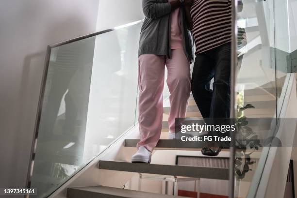 low section of a nurse helping a senior woman walking the stairs - old lady feet stockfoto's en -beelden