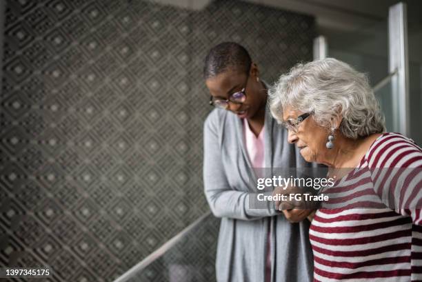 nurse helping a senior woman walking the stairs - home carer 個照片及圖片檔