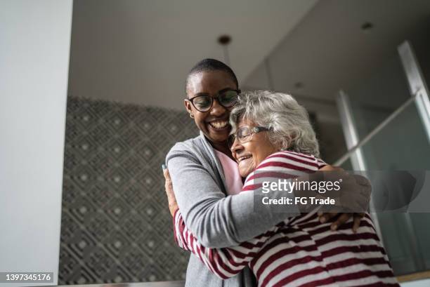 nurse helping a senior woman walking the stairs and embrace her - nurse candid stock pictures, royalty-free photos & images