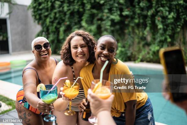 friends taking a photo holding drinks during pool party at home - chubby swimsuit stock pictures, royalty-free photos & images