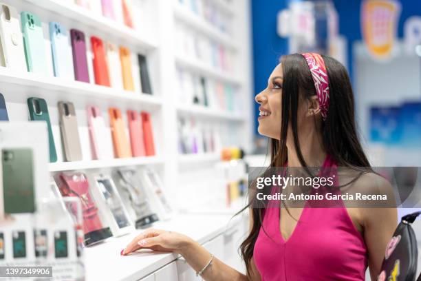 woman in a mobile phone and accessories store looks at the covers of the devices - exhibitor stock-fotos und bilder