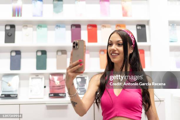 woman in a mobile phone and accessories store looks at the covers of the devices. mobile covers - exhibitor ストックフォトと画像