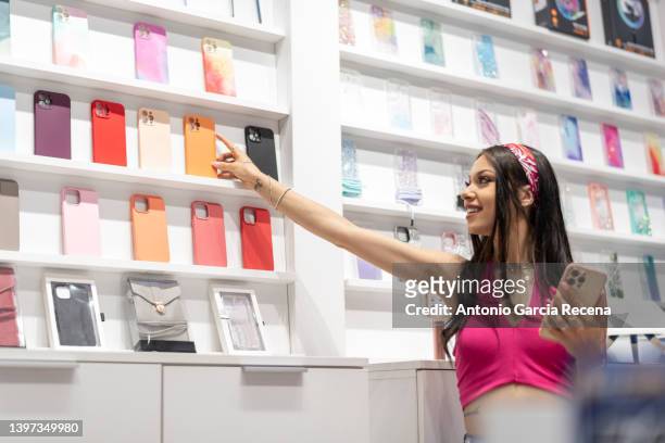 woman in a mobile phone and accessories store looks at the covers of the devices - utställare bildbanksfoton och bilder