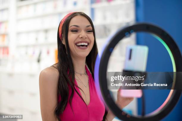 woman transmits content on the internet live through a mobile phone with a beauty dish and a tripod, live streaming by phone - ringflits stockfoto's en -beelden