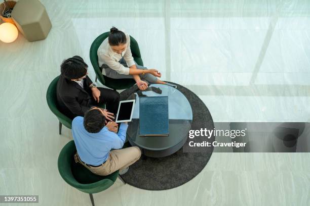 overhead view of  real estate agent shows new home to the young couple and discussing about home contract and decorate home on digital tablet. - real estate office stockfoto's en -beelden