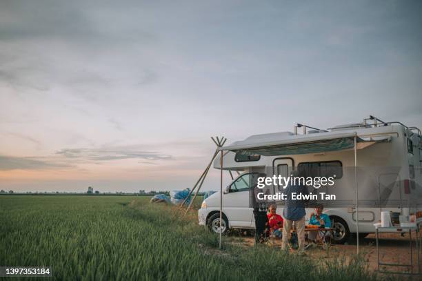 asian chinese senior friends enjoy dinner beside campervan parked at paddy field - campervan stockfoto's en -beelden