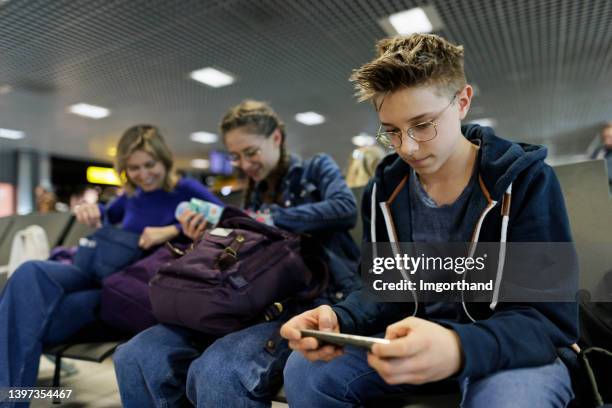 mother and teenagers waiting at the airport - game three stockfoto's en -beelden