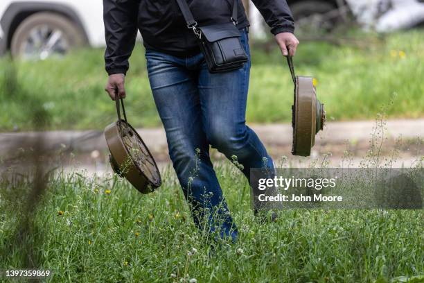 Civilian helps soldiers move anti-tank mines from a former frontline position to be relocated closer to Russian troops on May 15, 2022 on the...